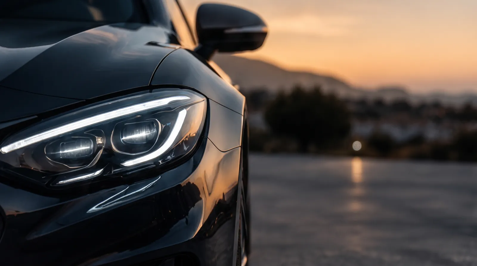 Coches a la carta: faro LED de un coche negro de gama alta al atardecer
